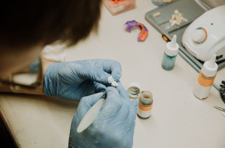 A dental technician shaping a ceramic restoration at the laboratory bench